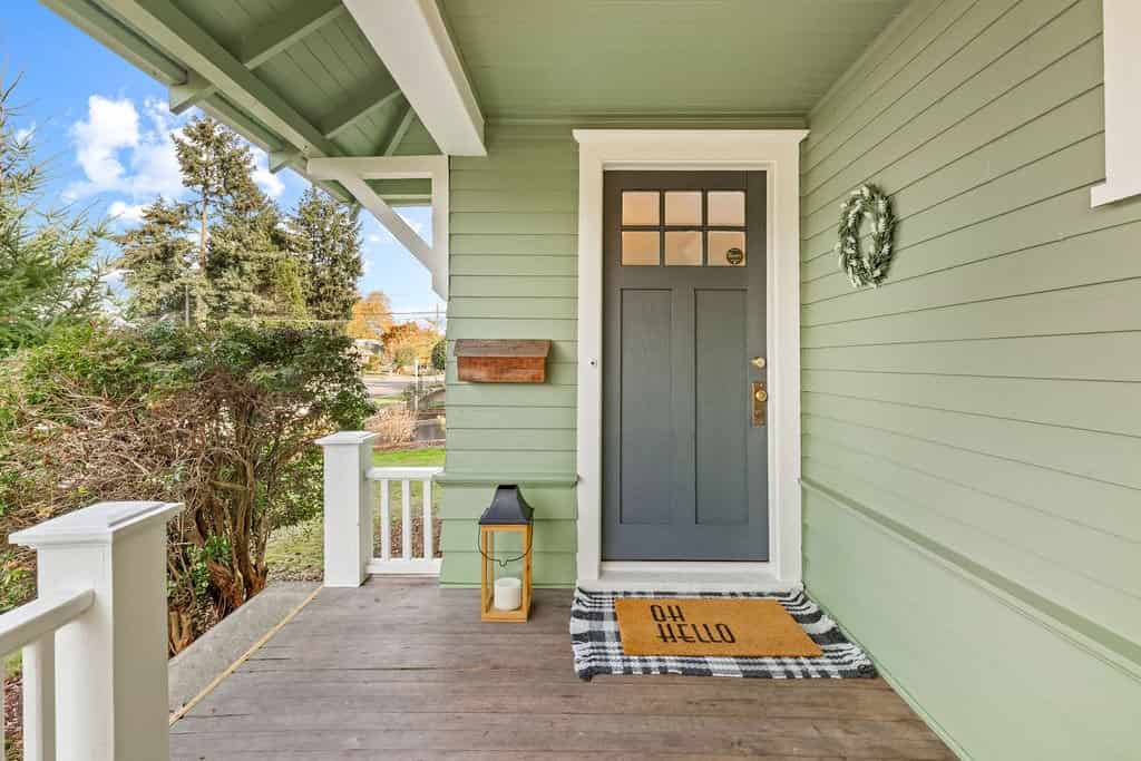 an image of a classy sage green house with wooden decking system